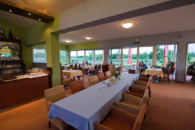 Bild mit gedeckter Tafel, Stühlen und Weinbar im Innenbereich des Golfclub-Restaurants.