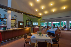 Innenbereich des Golfclub-Restaurants mit gedeckten Tischen und Stühlen.