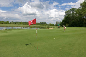 Tages-Greenfees. Bild mit Golfspieler nach seinem Putt, wobei der Ball das Ziel noch nicht erreicht hat.